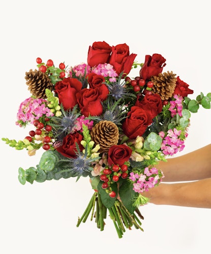 Vibrant bouquet featuring red roses, pink blooms, and natural accents like pine cones.