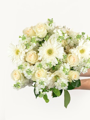 Elegant floral arrangement featuring white roses, gerbera daisies, and delicate greenery.