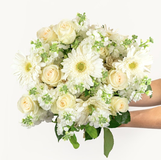 Elegant floral arrangement featuring white roses, gerbera daisies, and delicate greenery.