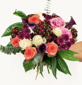 Vibrant floral bouquet featuring pink roses, purple calla lilies, and lush greenery.
