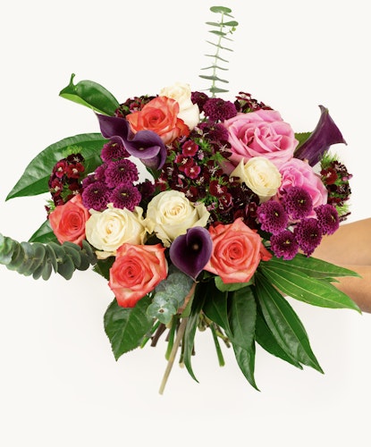 Vibrant floral bouquet featuring pink roses, purple calla lilies, and lush greenery.