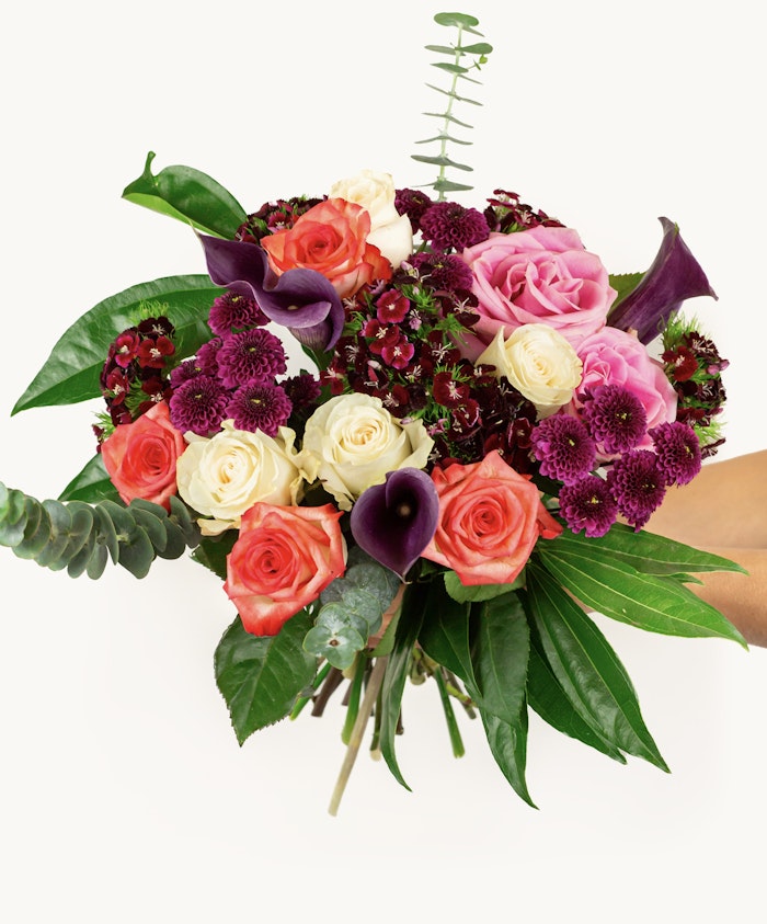 Vibrant floral bouquet featuring pink roses, purple calla lilies, and lush greenery.