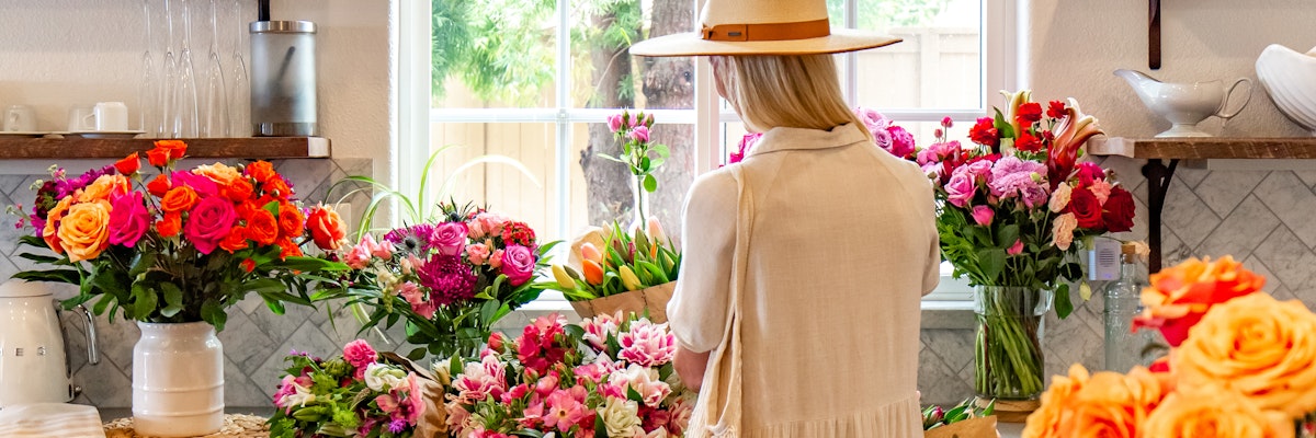 A florist arranging vibrant roses and blooms in a charming shop setting.