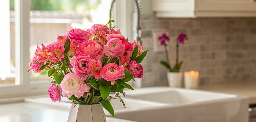 Bright bouquet of pink and white ranunculus flowers in a modern vase, enhancing kitchen décor.