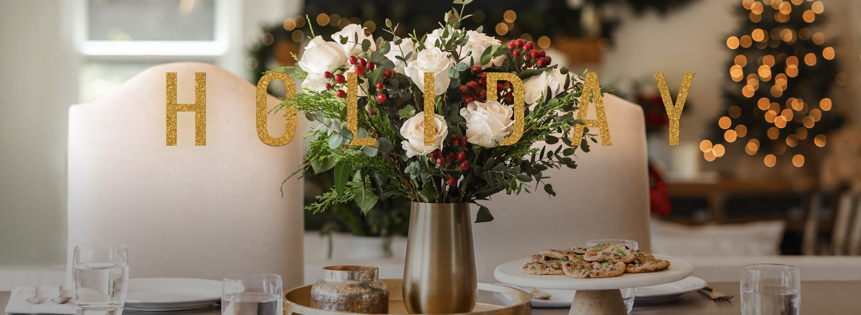 Elegant holiday table setting with white roses and festive decorations, perfect for gatherings.