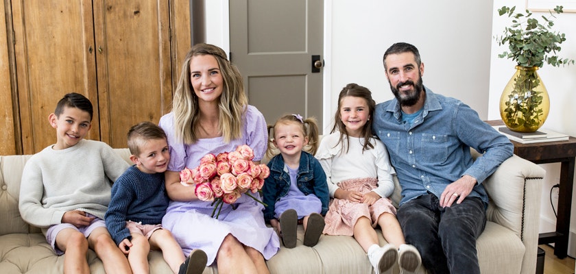 A cheerful family sitting on a sofa, celebrating with a bouquet of roses.