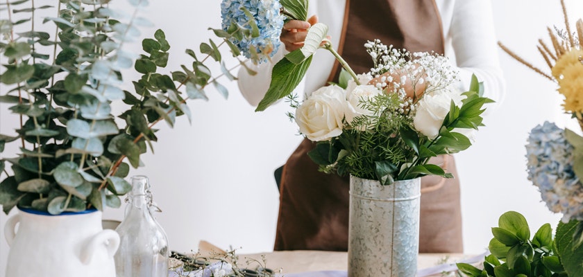 Floral designer creating a beautiful bouquet with hydrangeas, roses, and greenery.