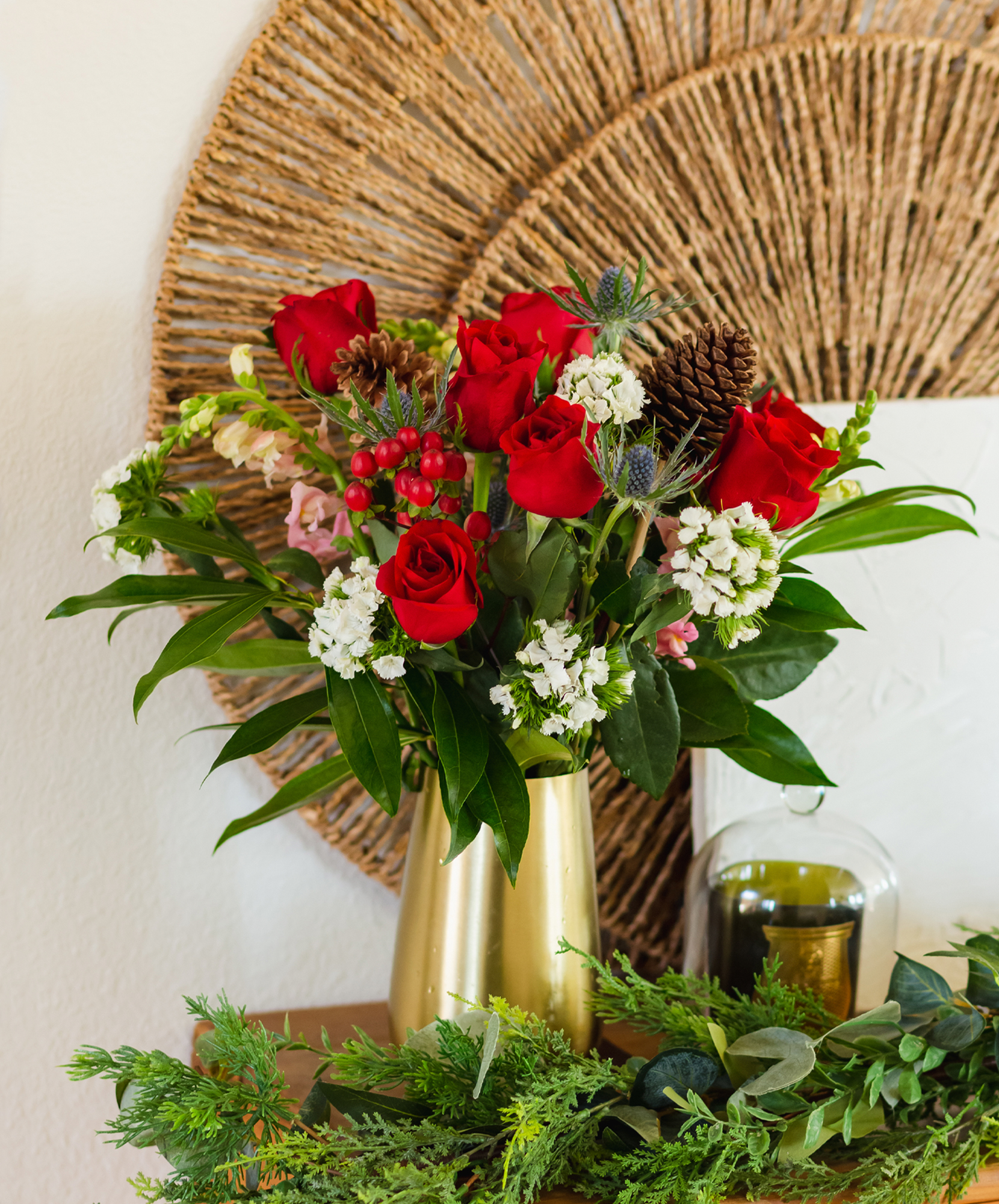 Vibrant red roses adorned with white flowers and greenery in a stylish vase.