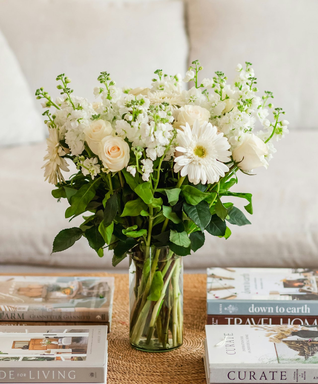 Elegant white floral bouquet featuring roses and gerbera daisies in a stylish glass vase.