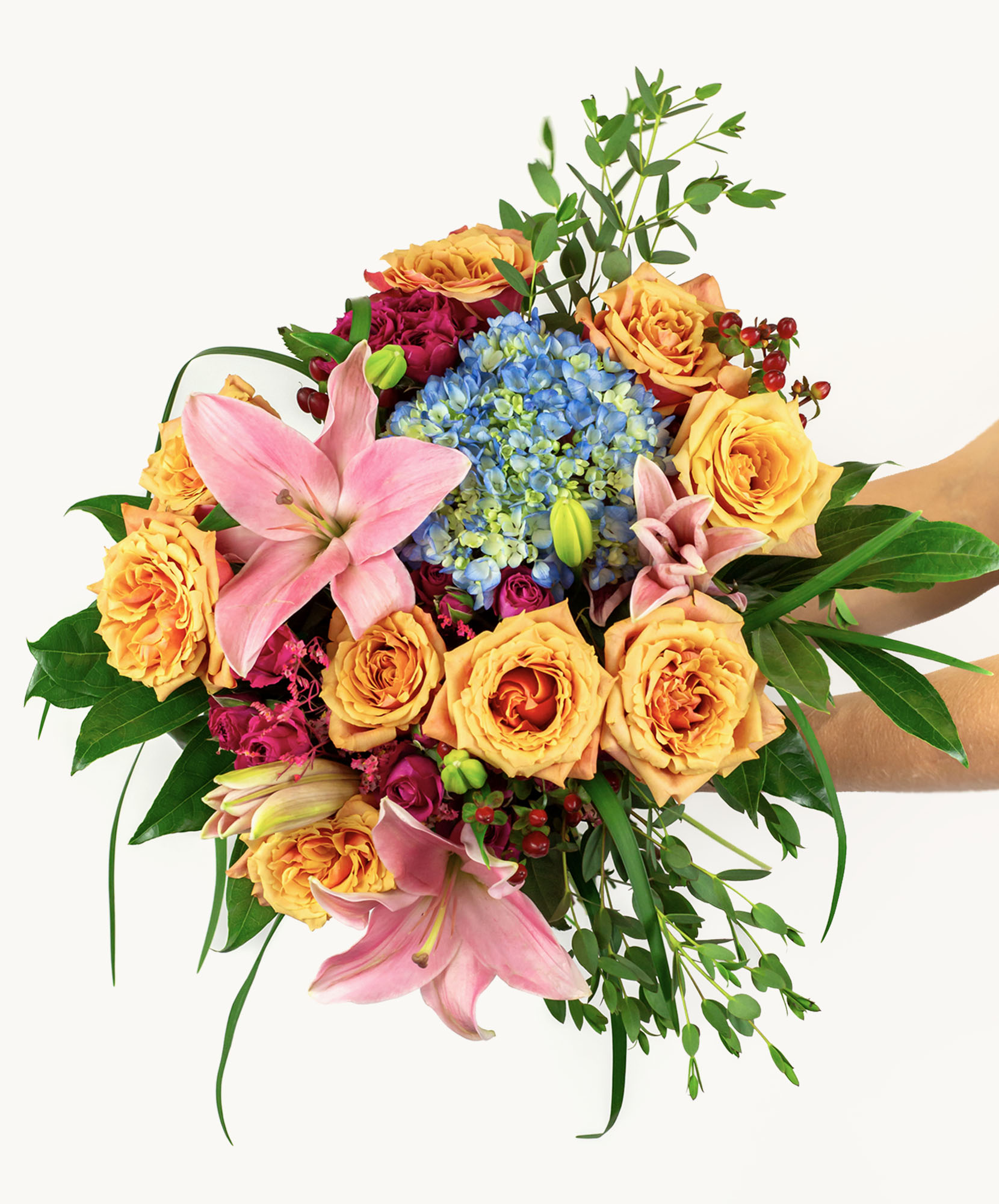 Vibrant floral bouquet featuring peach roses, pink lilies, and blue hydrangeas elegantly arranged.