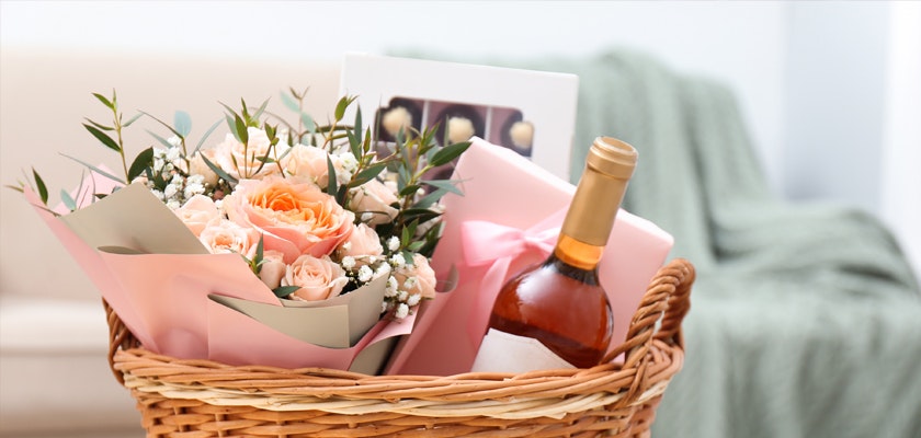 A lovely gift basket featuring pastel roses and a bottle of rosé wine, perfect for celebrations.