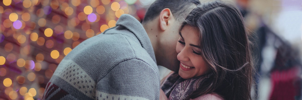 A joyful couple embracing warmly, surrounded by twinkling lights, capturing a romantic moment.