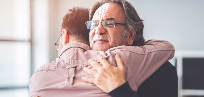 Emotional moment of a warm embrace between a father and son in a bright room.