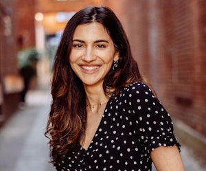 Smiling woman in a polka dot dress, posing in a charming urban alleyway.