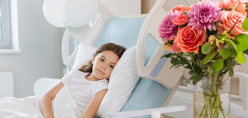 A cheerful bouquet of colorful flowers beside a young girl resting in a hospital bed.