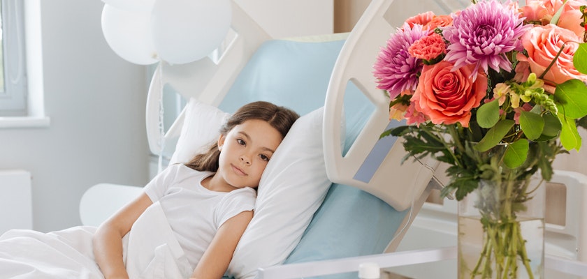 A cheerful bouquet of colorful flowers beside a young girl resting in a hospital bed.