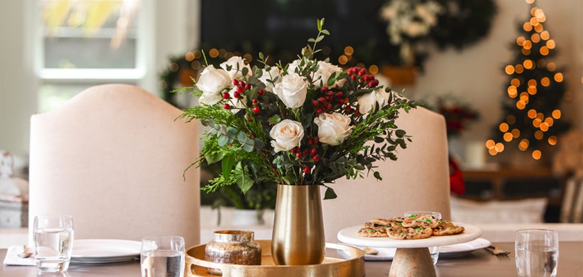 Elegant white rose bouquet with greenery, set on a festive dining table with cookies.