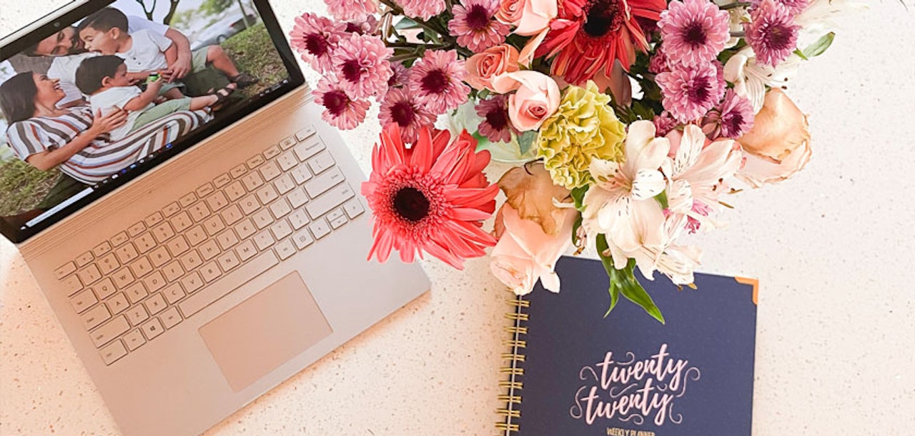 A vibrant floral arrangement atop a workspace with a laptop and planner, perfect for inspiration.