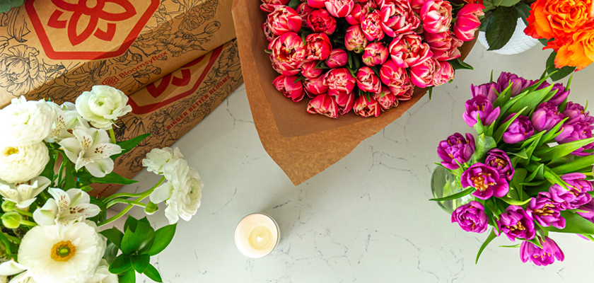 Vibrant floral arrangement featuring tulips, peonies, and roses on a marble surface.