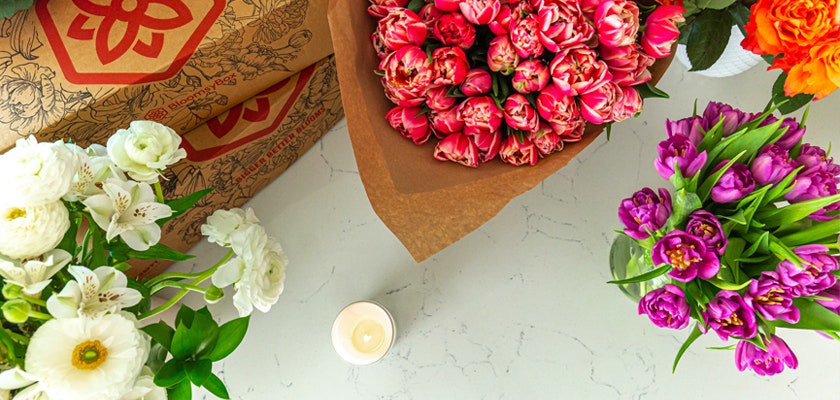 Vibrant floral arrangement featuring tulips, peonies, and roses on a marble surface.