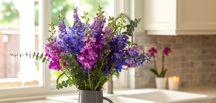 Vibrant bouquet of purple and blue flowers elegantly displayed in a kitchen vase, enhancing decor.