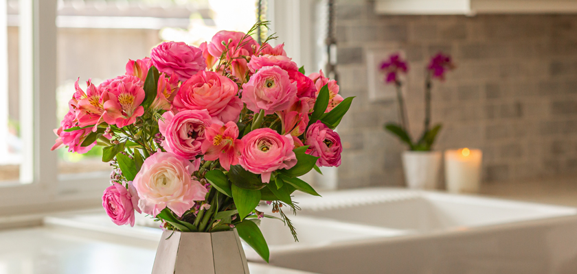 Elegant pink roses and alstroemeria arranged in a stylish vase, brightening a modern kitchen.