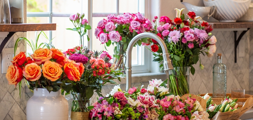 Vibrant floral arrangement featuring roses and mixed blooms in a bright kitchen setting.