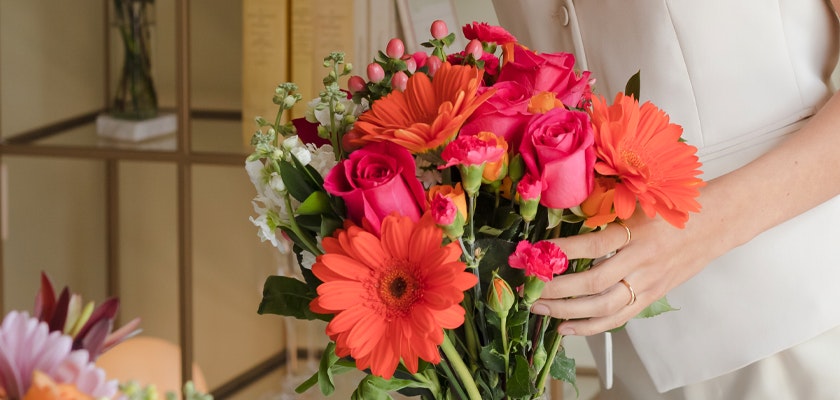 Vibrant mixed flower bouquet featuring pink roses, gerbera daisies, and orange blooms.