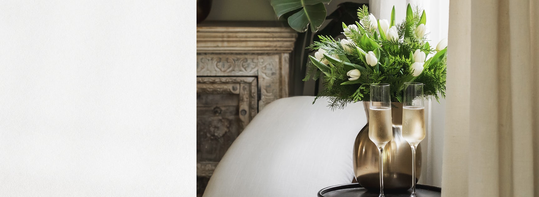 Elegant floral arrangement with white blooms and greenery beside champagne flutes.