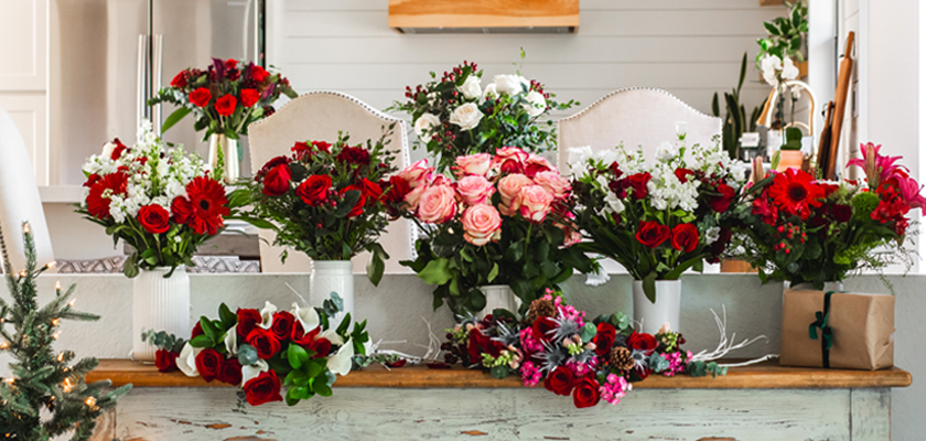 Vibrant floral arrangements featuring red roses, pink blooms, and lush greenery on display.