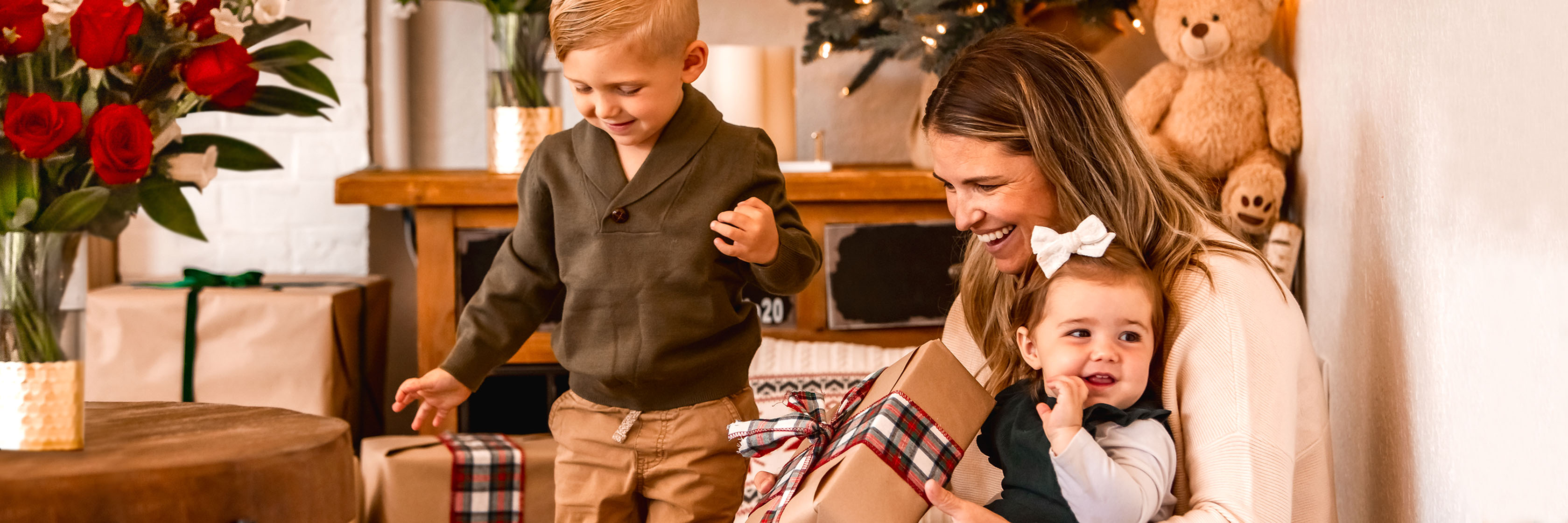 A joyful family moment with a mother and her kids, surrounded by holiday gifts and flowers.