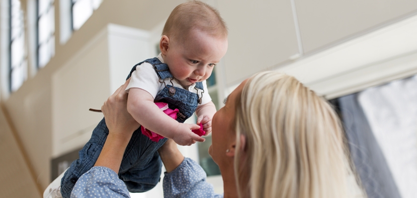 A joyful mother lifts her baby, sharing a tender moment filled with love and connection.