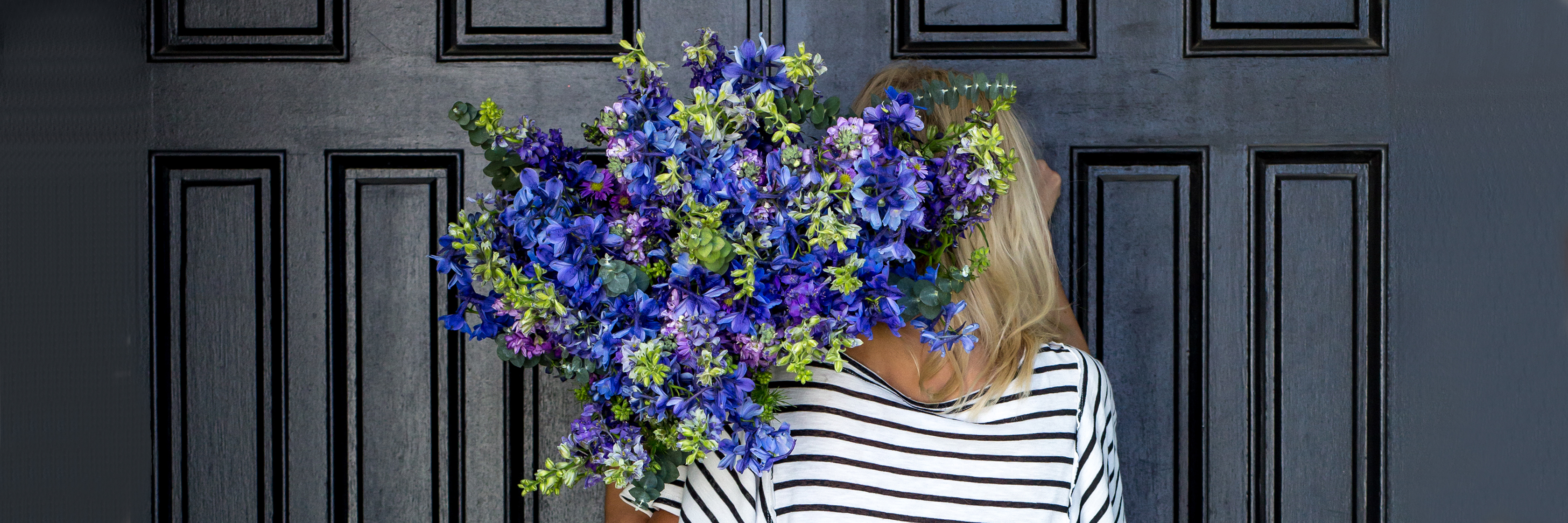 A vibrant bouquet of blue and purple flowers, perfectly complementing a stylish outfit.