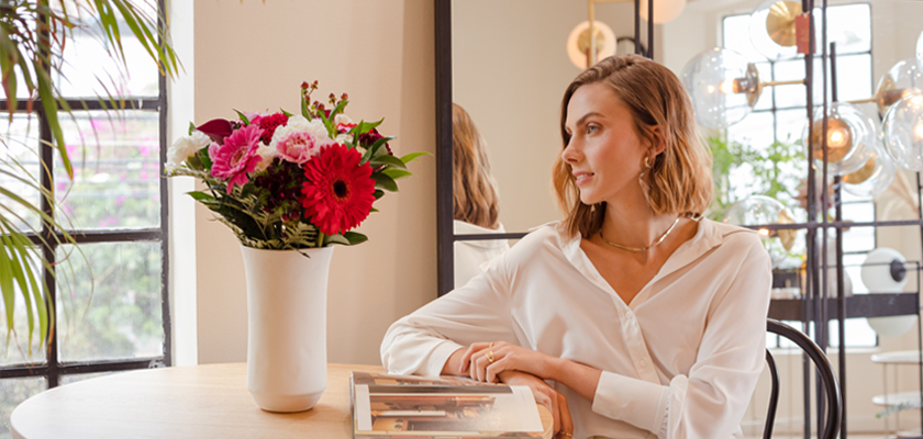 A stylish woman admiring a vibrant flower bouquet in a chic, modern setting.