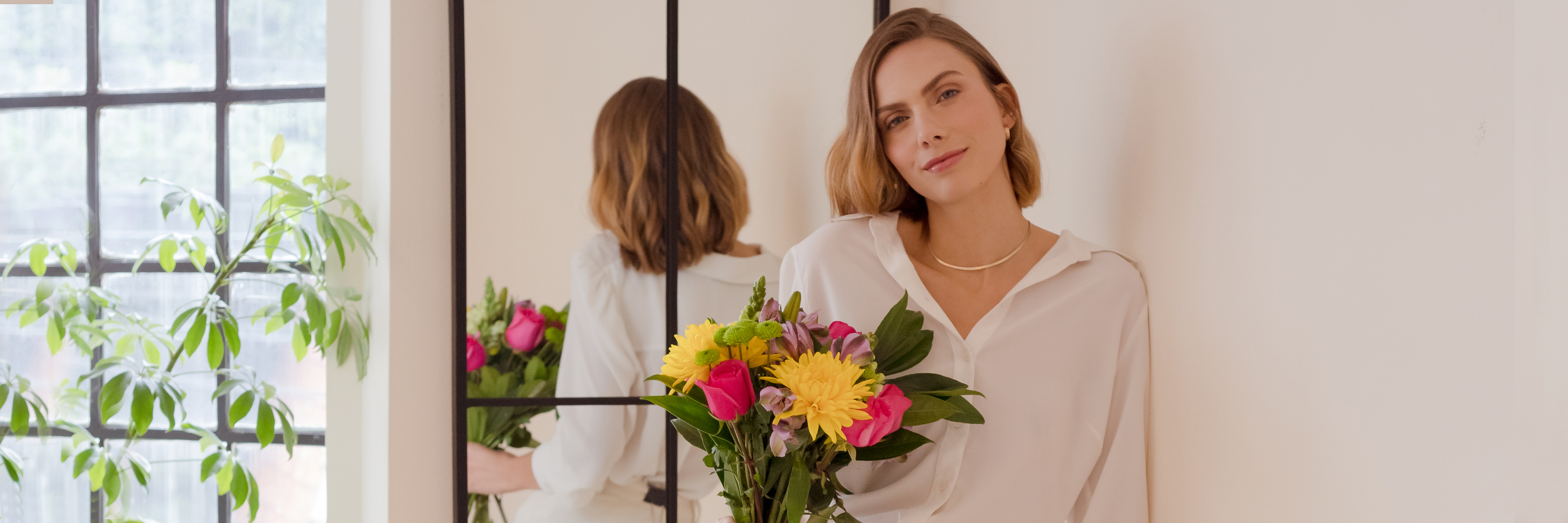 A woman in a white blouse holding a vibrant floral bouquet with colorful blooms.