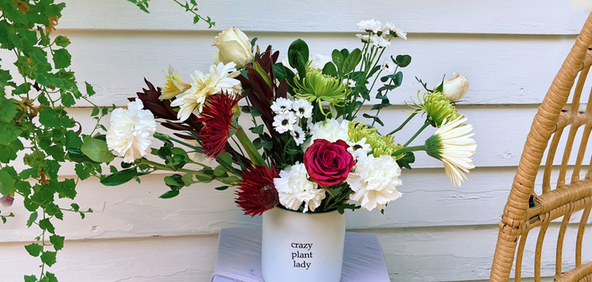 Vibrant floral arrangement in a charming pot featuring roses, daisies, and more.