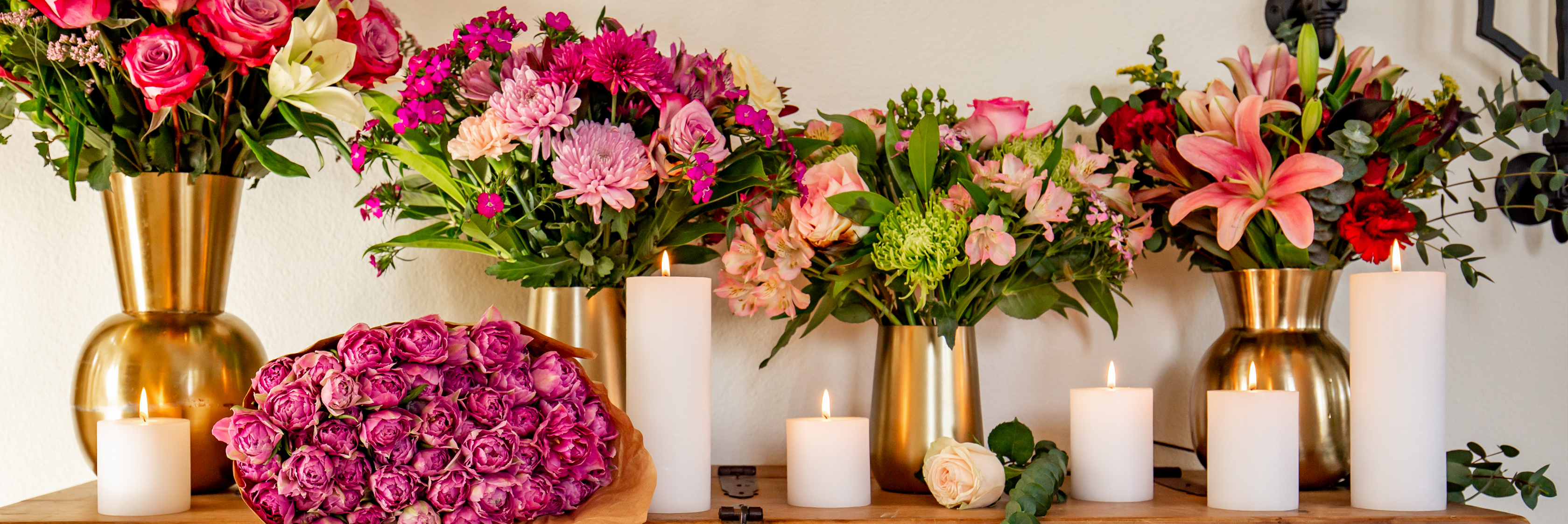 Elegant floral display featuring vibrant pink flowers and soft candles, perfect for home decor.