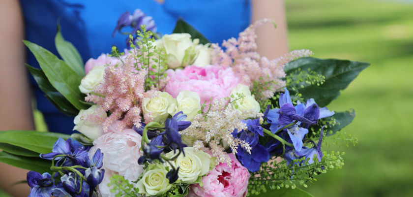 A vibrant bouquet featuring pink peonies, blue delphiniums, and delicate greenery.