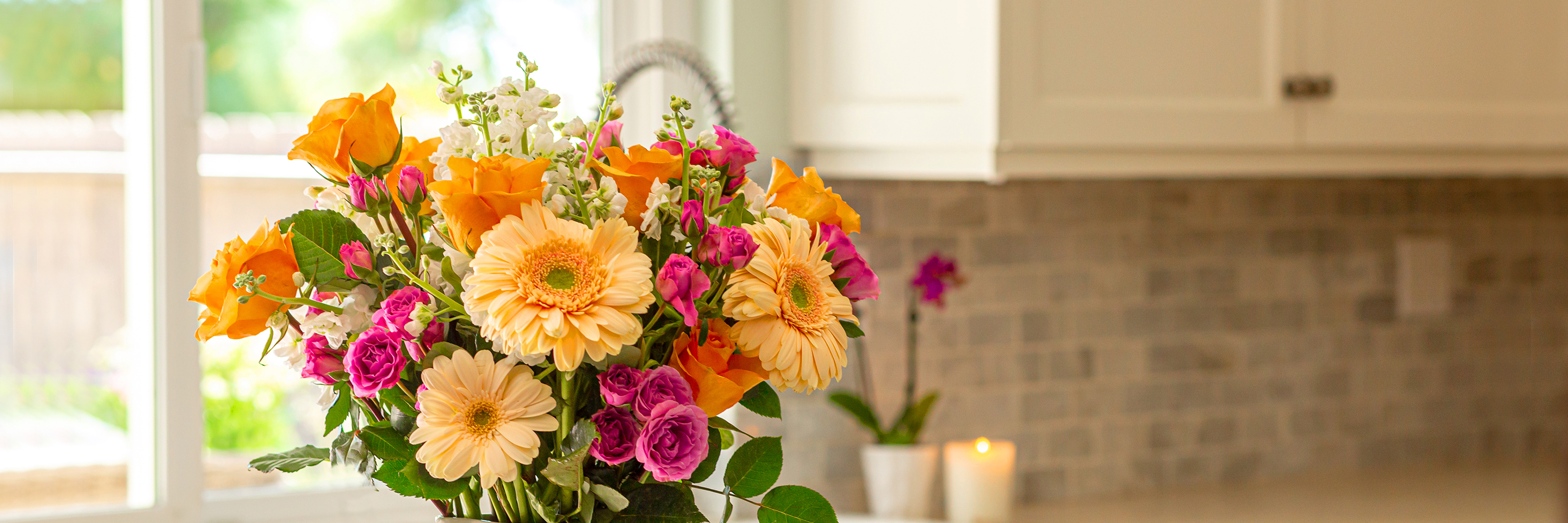 Vibrant floral arrangement featuring yellow gerbera daisies and pink roses on a kitchen counter.