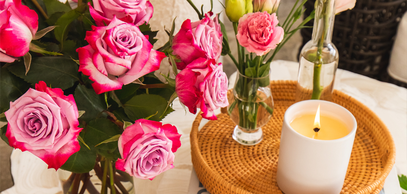 Vibrant arrangement of pink and lavender roses with soft candles on a stylish table setting.
