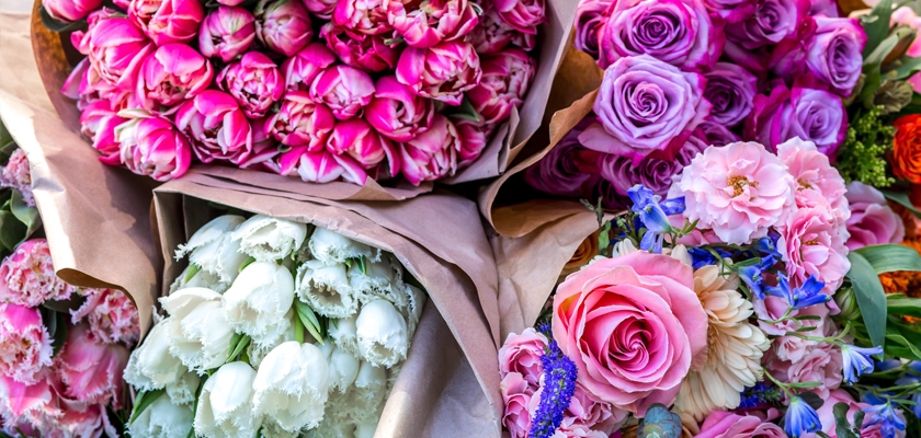 Vibrant floral display featuring pink roses, tulips, and assorted blooms in elegant packaging.