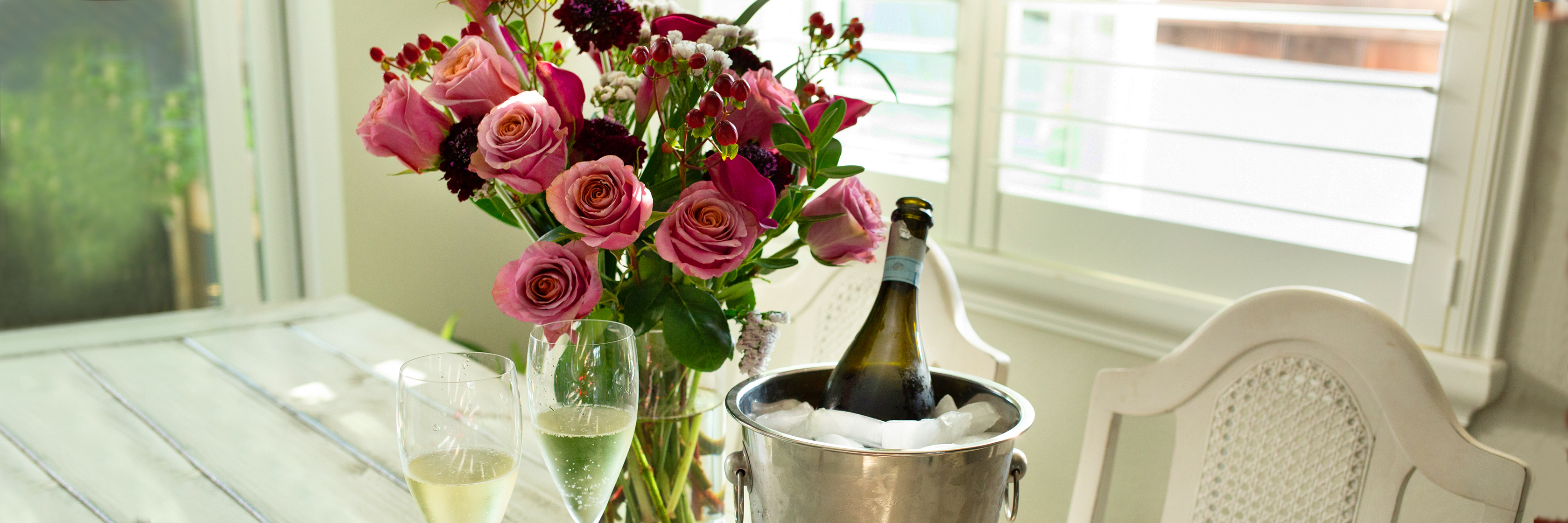 Elegant bouquet of pink roses with champagne in an ice bucket, perfect for celebrations.