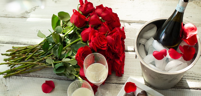 Elegant red roses with champagne and chocolates, perfect for a romantic celebration.