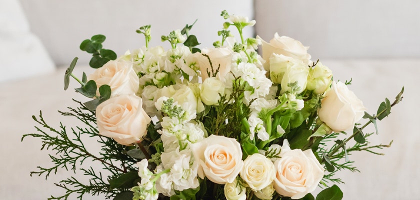 Elegant bouquet of pale roses, white blooms, and lush greenery in a stylish arrangement.