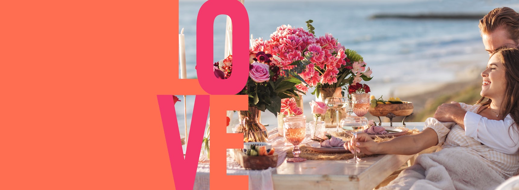 A romantic seaside dinner setup with vibrant floral arrangements and happy couple.