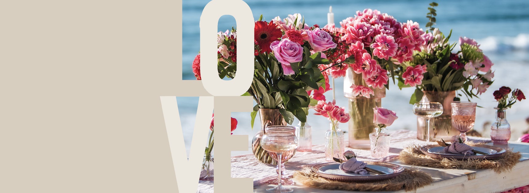 A romantic beachside table setting adorned with vibrant floral arrangements and elegant glassware.