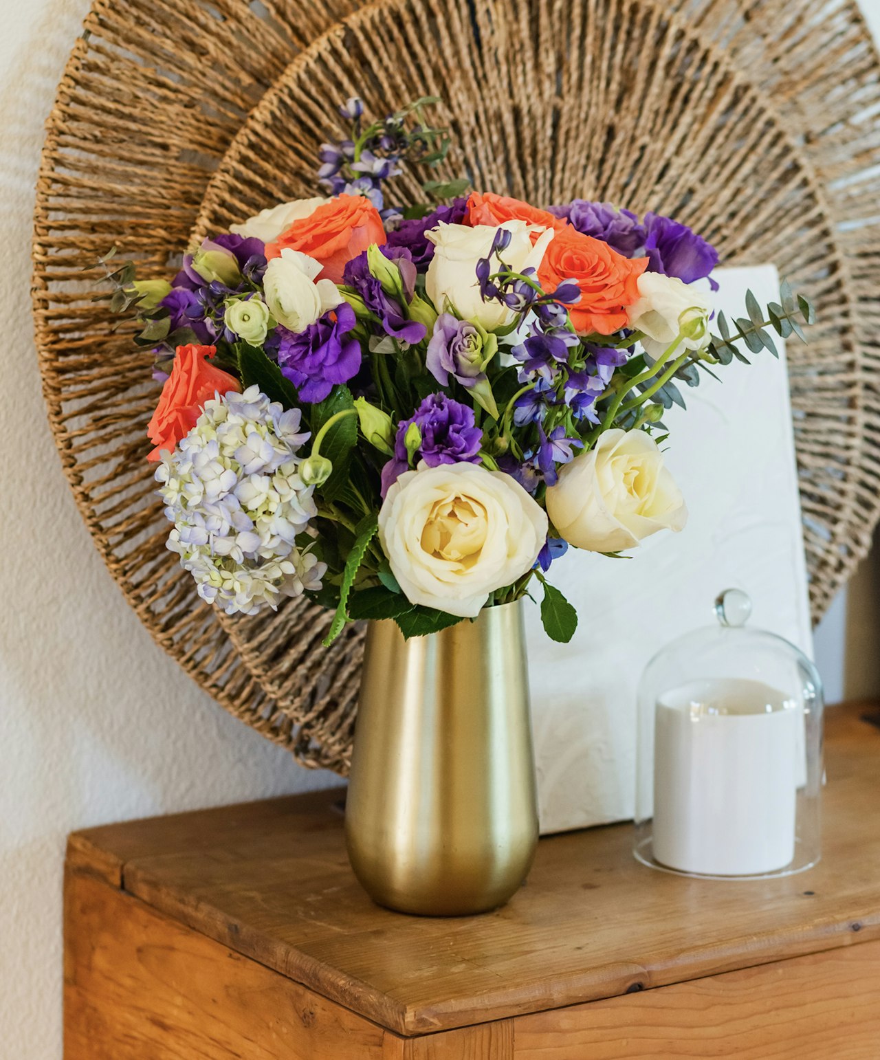 Vibrant floral arrangement featuring roses, lisianthus, and blooms in a chic gold vase.