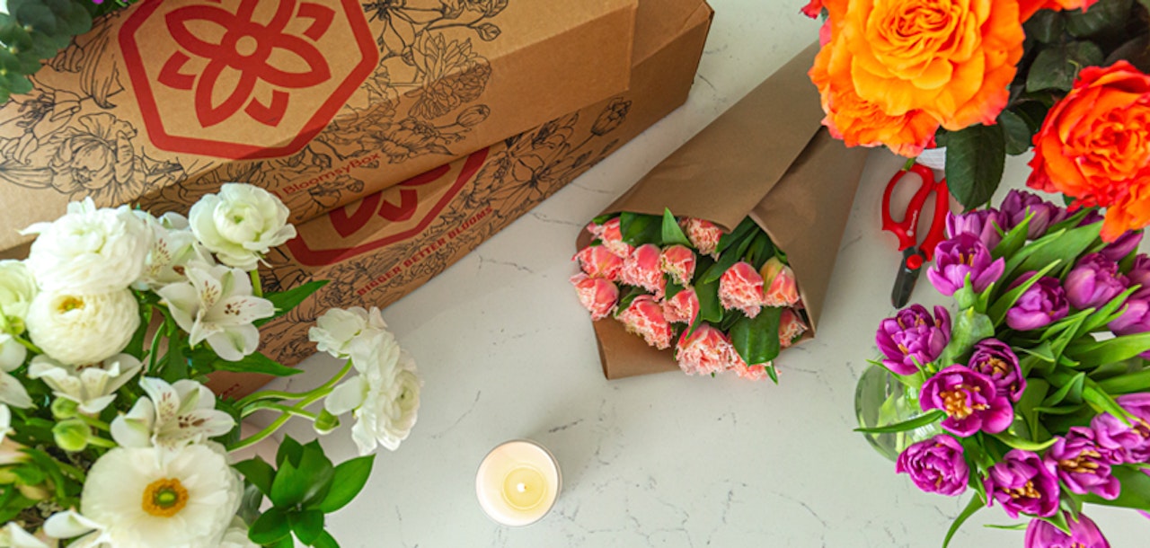 Colorful floral arrangement featuring vibrant roses, tulips, and lilies in elegant packaging.