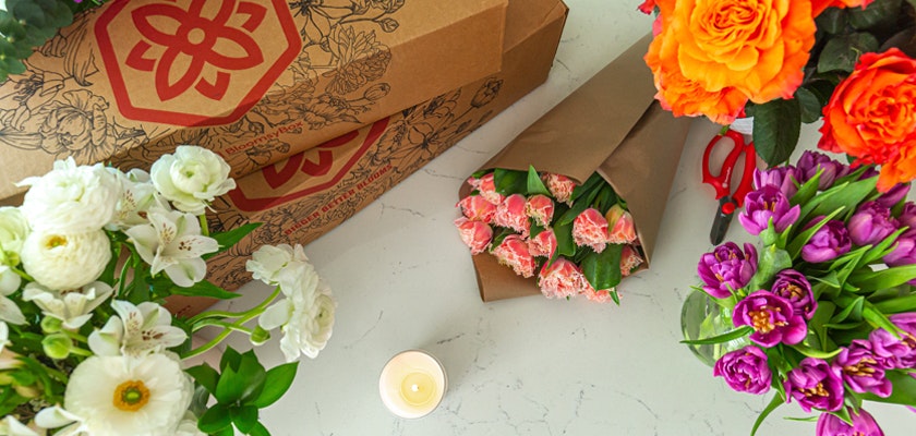 Colorful floral arrangement featuring vibrant roses, tulips, and lilies in elegant packaging.