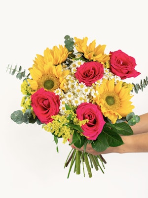 Colorful bouquet featuring vibrant sunflowers, pink roses, and greenery, perfect for celebrations.